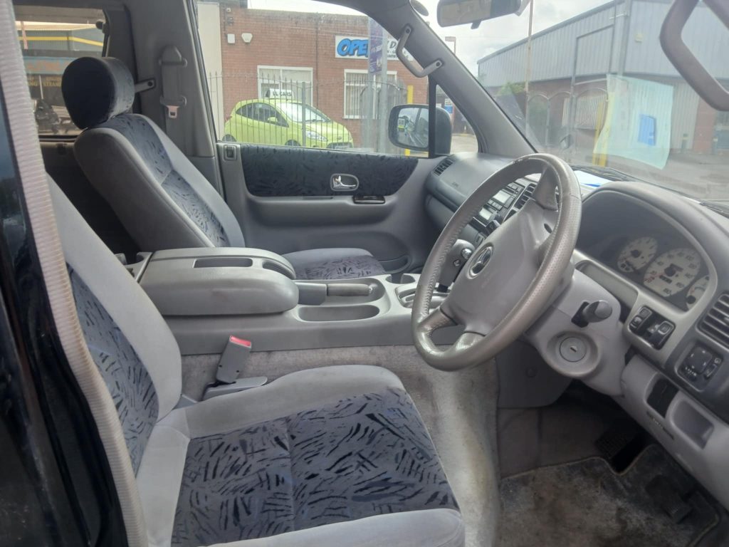 Interior view of a Mazda Bongo campervan conversion, showcasing seating and storage layout.