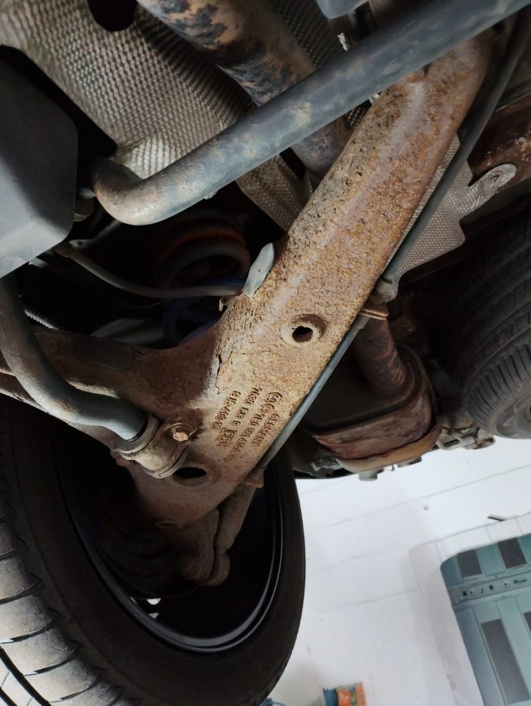 Close-up of VW T6 suspension arm and chassis before rust protection and underseal service
