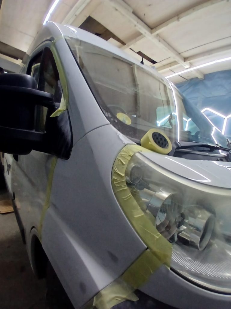 Close-up of Citroën Relay body panels masked and sanded for primer application