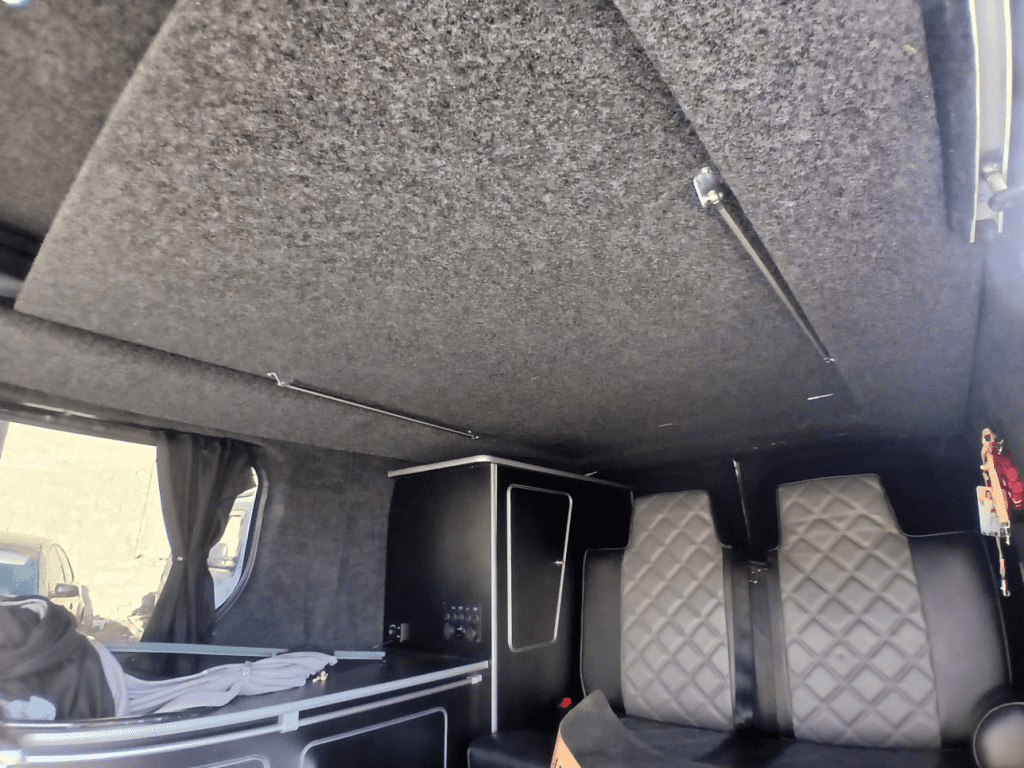 Front view of the Vauxhall Vivaro with the newly installed pop-top roof raised inside the workshop