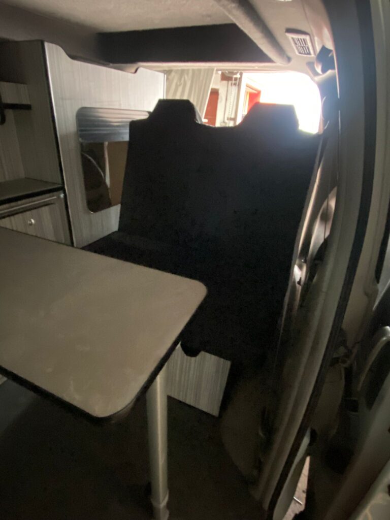 Modern campervan interior showing seating area and fold-out table system installed