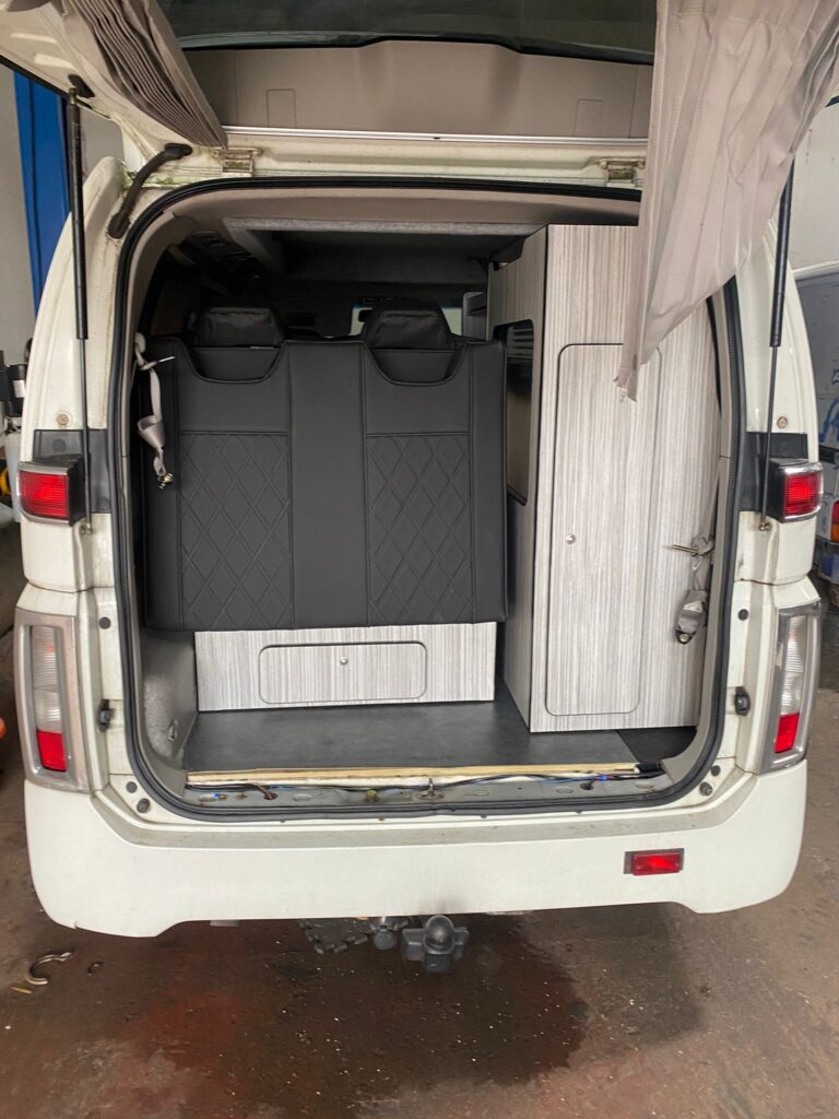Rock and roll bed setup in campervan with upholstered seating and rear layout