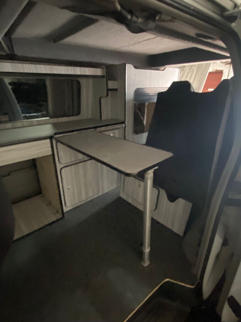 Rock and roll bed setup in campervan with upholstered seating and rear layout