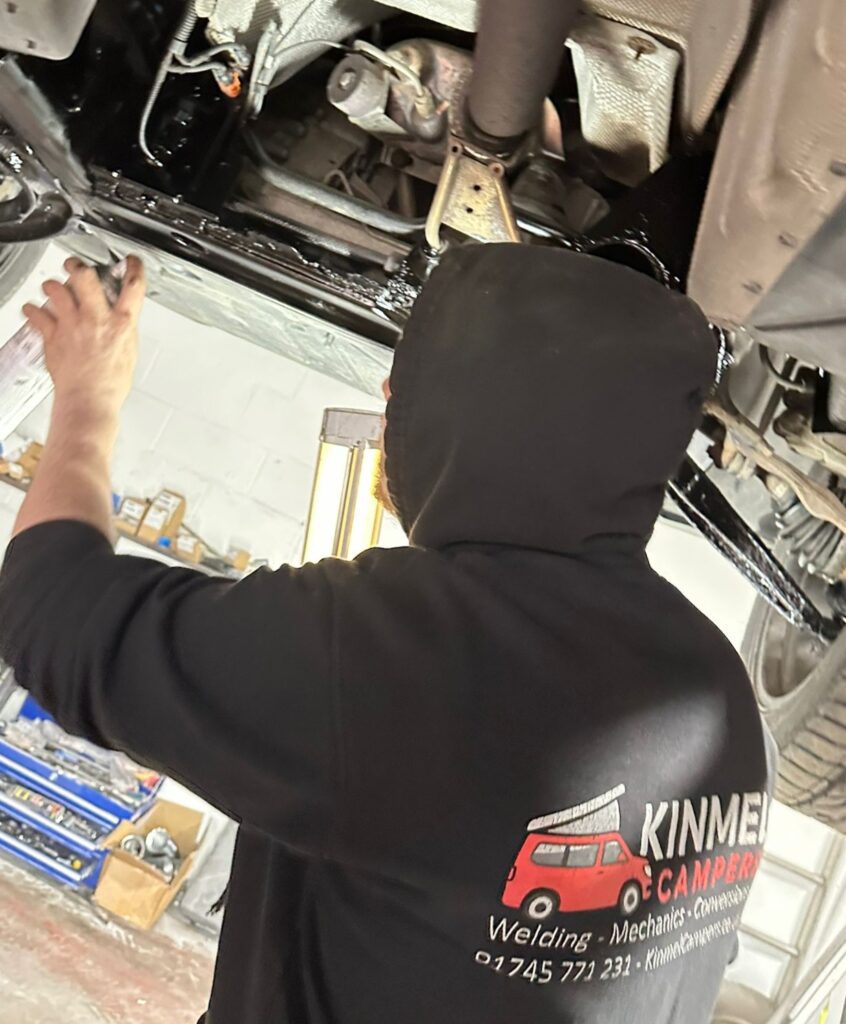 VW T5 underseal application in progress with technician protecting chassis for long-term corrosion prevention