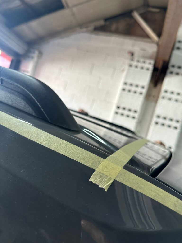 Close-up of Volkswagen Caddy roof with masking tape marking cut line for pop top installation