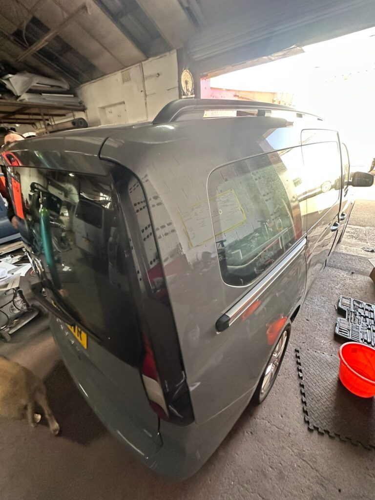 Volkswagen Caddy in workshop before pop top installation showing full vehicle exterior at Kinmel Campers
