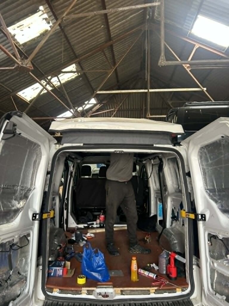 Interior view of Ford Transit Custom pop top roof and bi-fold bed platform during campervan conversion