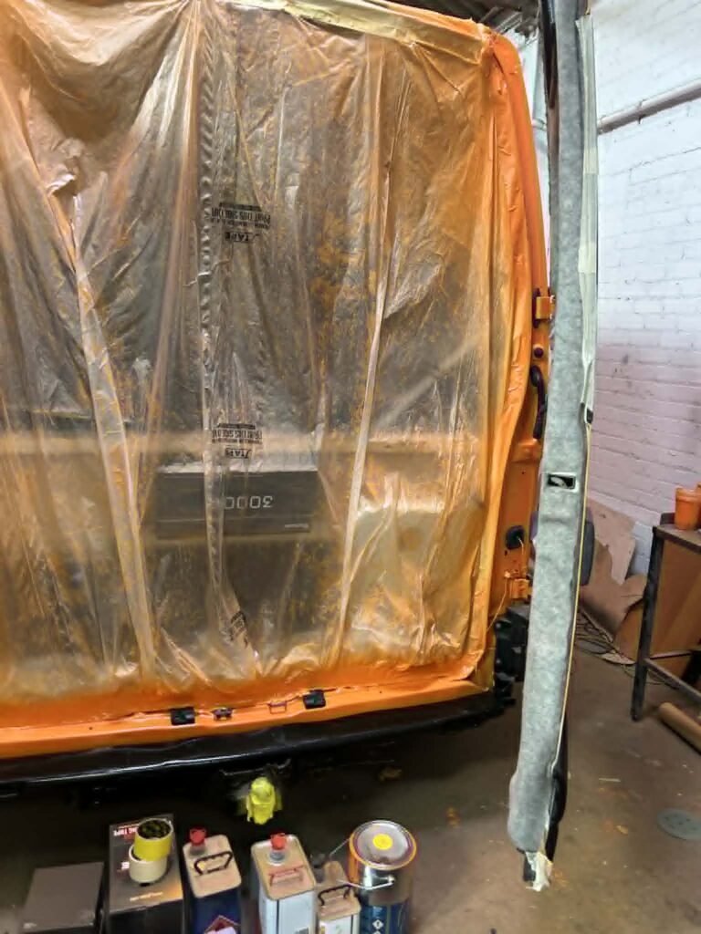 Rear of campervan masked during bright orange respray preparation